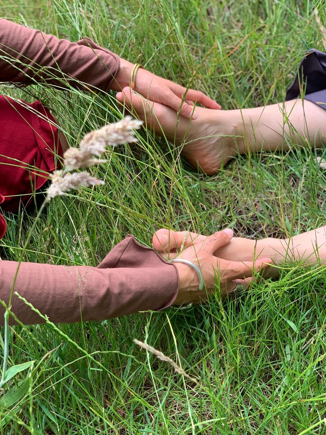 Hands resting gently on a person's feet in long grass